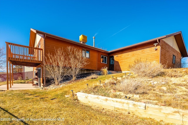 view of property exterior featuring a wooden deck and a yard