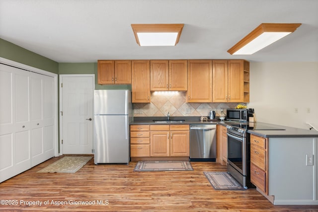 kitchen with backsplash, sink, light hardwood / wood-style floors, and appliances with stainless steel finishes