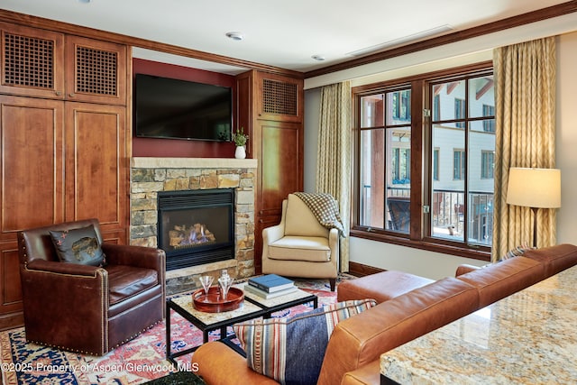 living room featuring a stone fireplace and crown molding