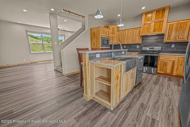 118 Highland Dr, Craig, CO 81625 - kitchen with stainless steel appliances, open shelves, a center island with sink, wood finished floors, and backsplash