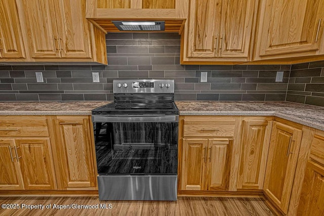 118 Highland Dr, Craig, CO 81625 - kitchen featuring stainless steel range with electric stovetop, decorative backsplash, range hood, and wood finished floors