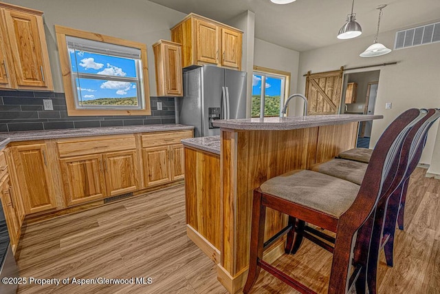 118 Highland Dr, Craig, CO 81625 - kitchen featuring stainless steel fridge with ice dispenser, light wood-style floors, backsplash, a barn door, and plenty of natural light