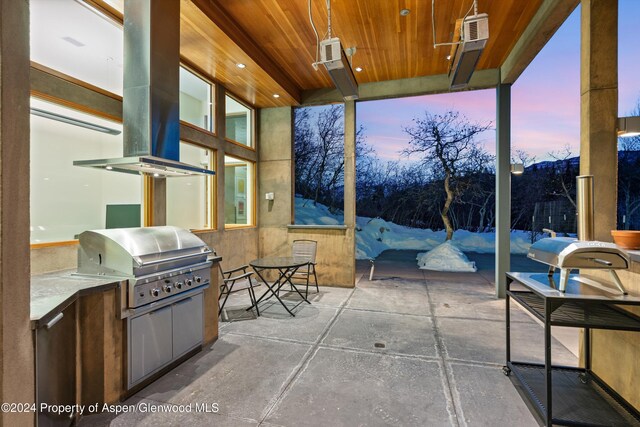 patio terrace at dusk with area for grilling and exterior kitchen