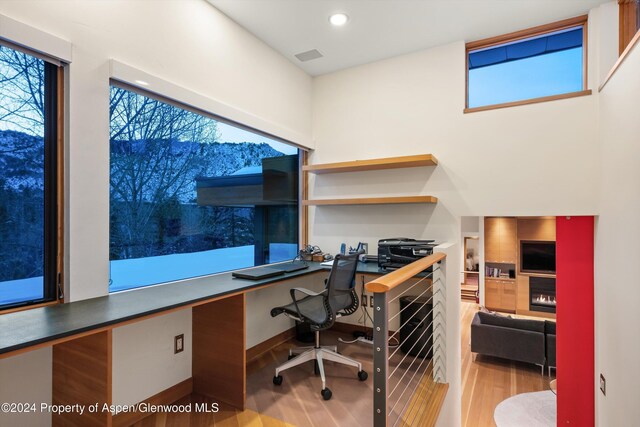 office space with built in desk and light hardwood / wood-style floors