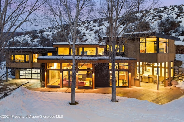 snow covered back of property featuring a mountain view