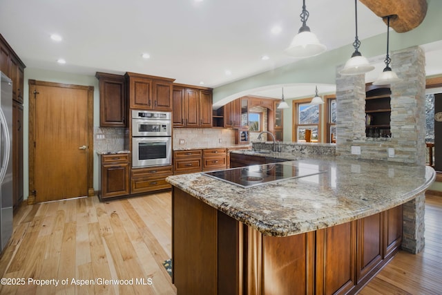 kitchen with decorative backsplash, light wood-style flooring, decorative light fixtures, black electric stovetop, and double oven