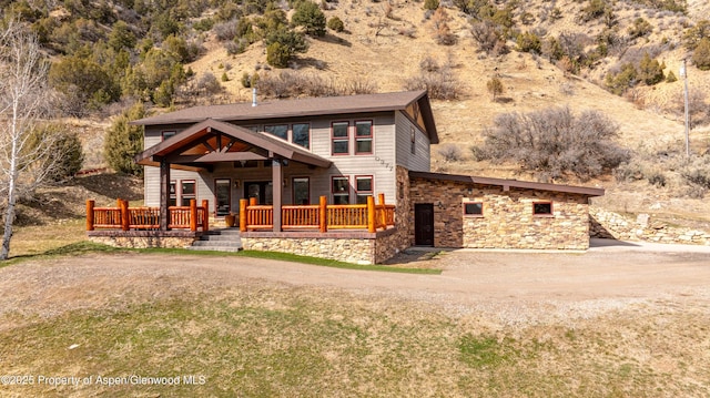 view of front of property featuring stone siding, a front lawn, and driveway