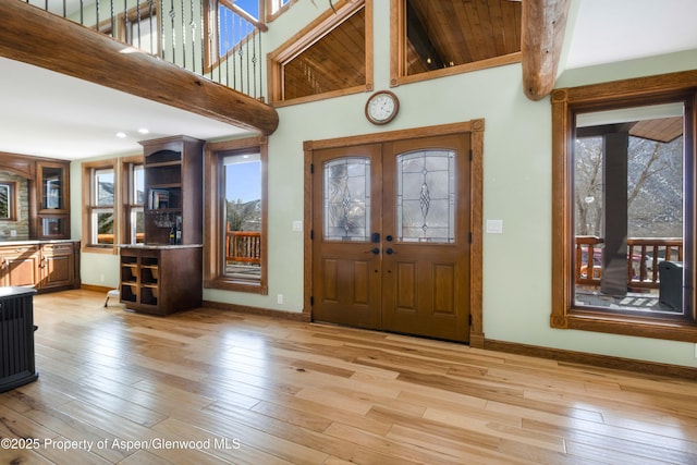 entryway featuring light wood-style flooring, a high ceiling, baseboards, and french doors