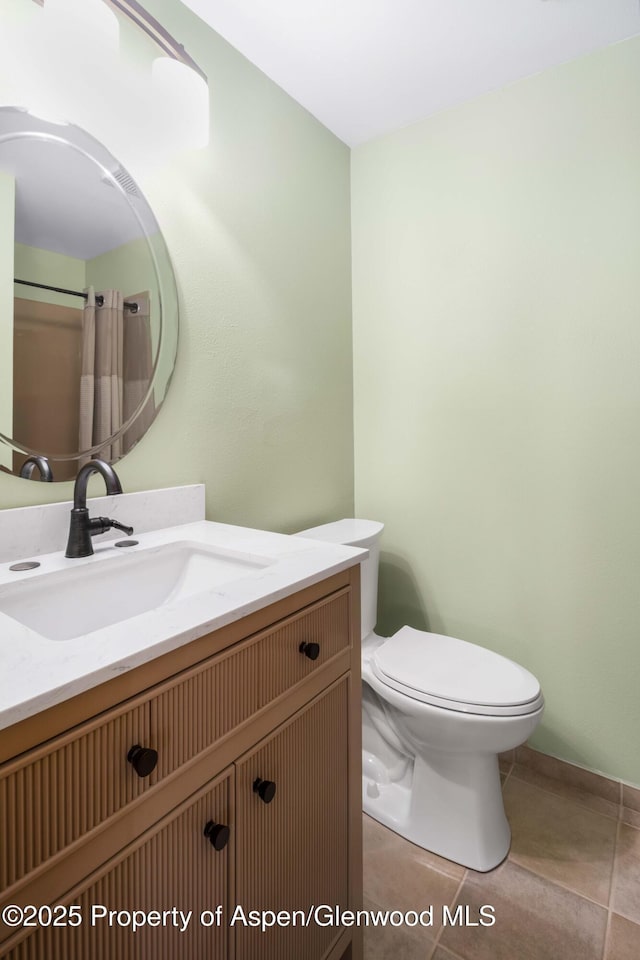 bathroom with toilet, vanity, and tile patterned floors