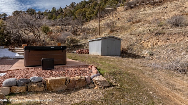 view of yard featuring a hot tub, a shed, and an outbuilding