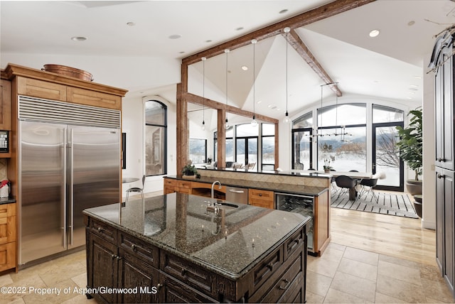 2908 Juniper Hill Dr, Aspen, CO 81611 - kitchen featuring built in appliances, wine cooler, a kitchen island with sink, vaulted ceiling, and healthy amount of natural light