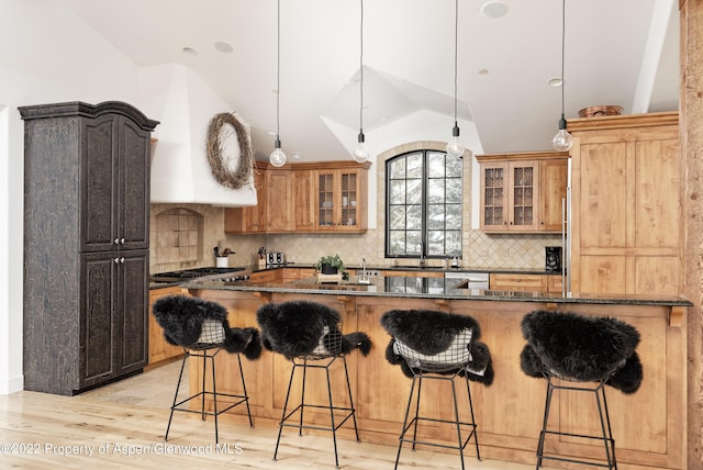 2908 Juniper Hill Dr, Aspen, CO 81611 - kitchen featuring a kitchen breakfast bar, glass insert cabinets, vaulted ceiling, and light wood finished floors