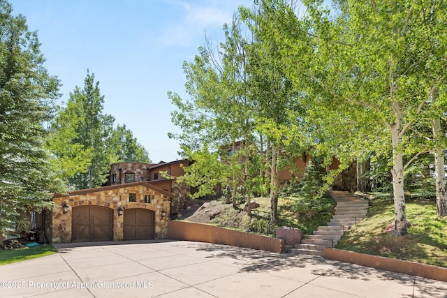 2908 Juniper Hill Dr, Aspen, CO 81611 - view of front of property with stone siding, concrete driveway, an attached garage, stairway, and stucco siding