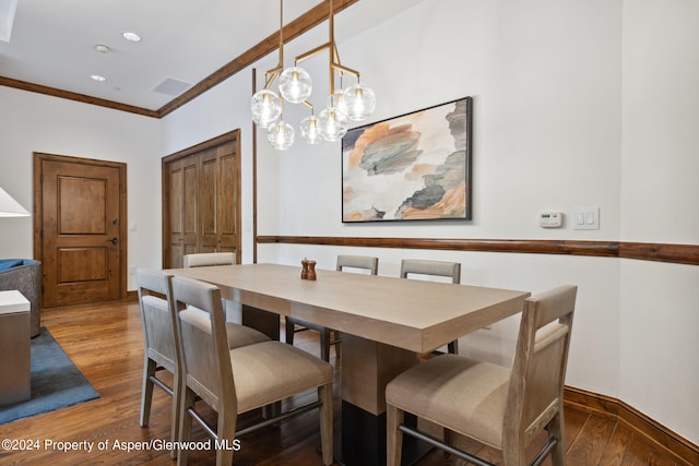 dining room with dark hardwood / wood-style flooring, ornamental molding, and an inviting chandelier