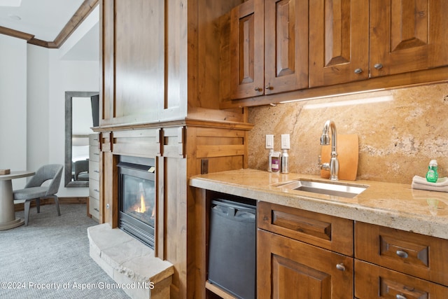 kitchen with dishwasher, sink, light stone counters, backsplash, and crown molding