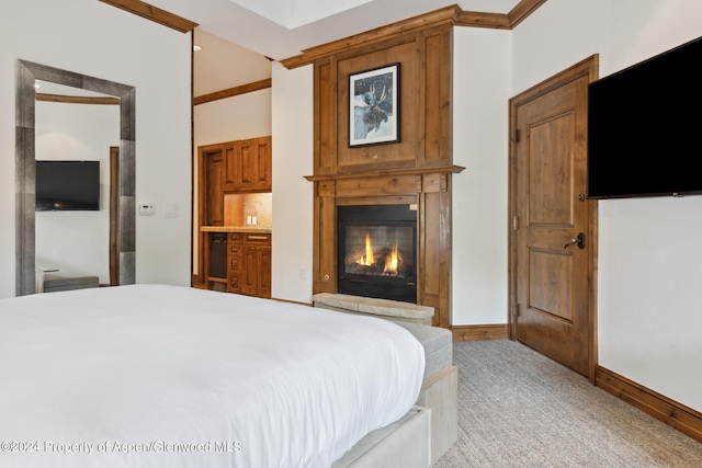 bedroom featuring ensuite bathroom, light colored carpet, a fireplace, and crown molding