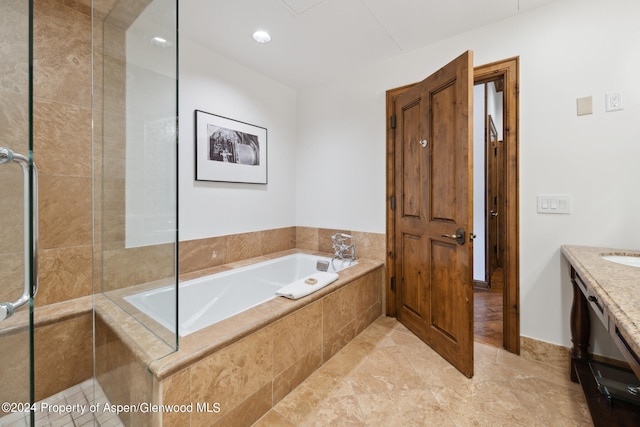 bathroom featuring vanity and tiled bath