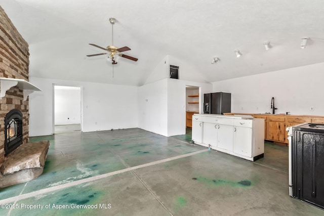 40889 County Road 76a, Hayden, CO 81639 - unfurnished living room featuring finished concrete floors, ceiling fan, a sink, a stone fireplace, and high vaulted ceiling