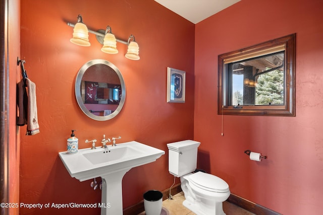 bathroom with toilet, baseboards, and a sink