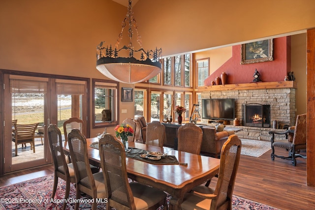 dining room with a high ceiling, a fireplace, and wood finished floors