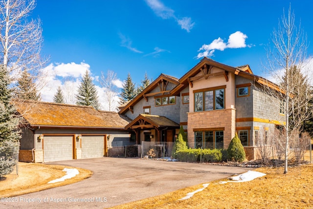 view of front facade with an attached garage, stone siding, and aphalt driveway