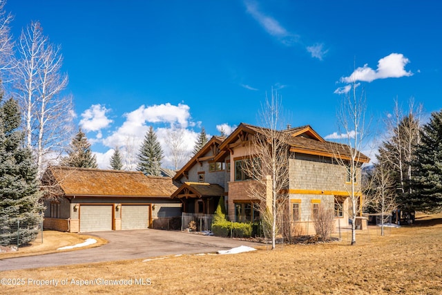 view of front of house with a garage, stone siding, and driveway