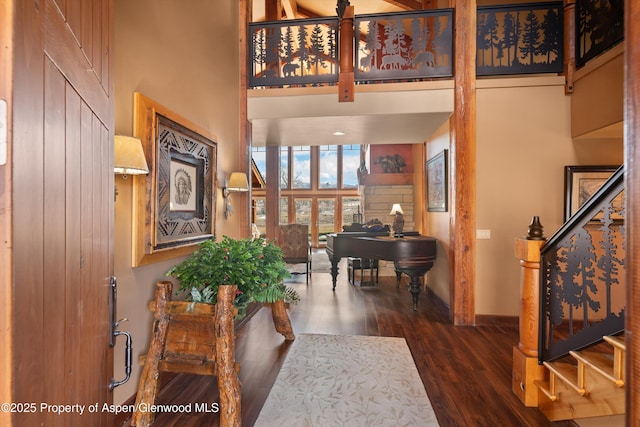 foyer entrance with stairs, a towering ceiling, baseboards, and wood finished floors