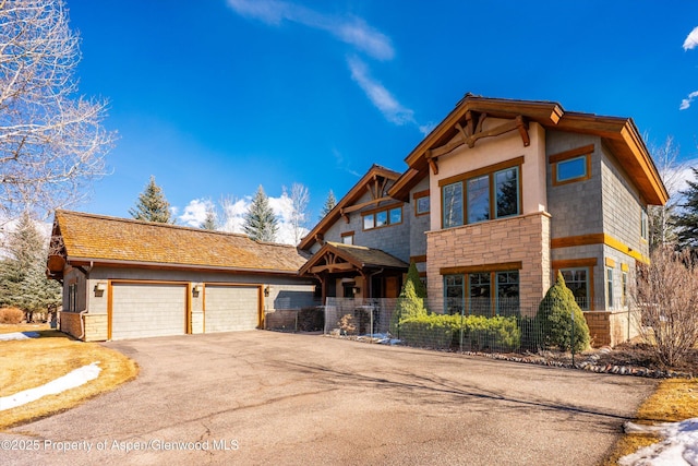 view of front facade featuring aphalt driveway, stone siding, and a garage