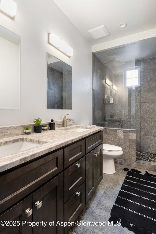 full bathroom featuring a walk in shower, double vanity, a sink, and toilet