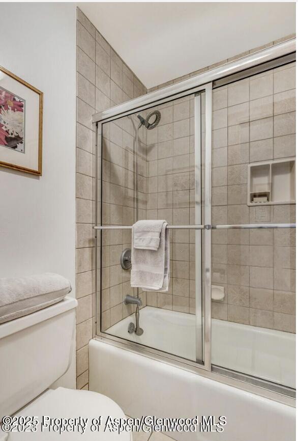 bathroom featuring shower / bath combination with glass door and toilet