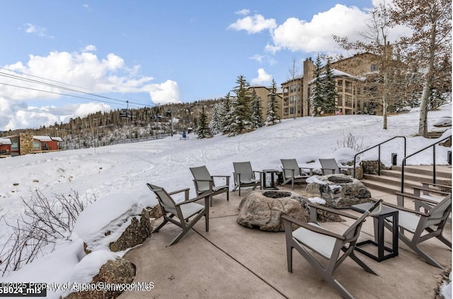 snow covered patio featuring an outdoor fire pit