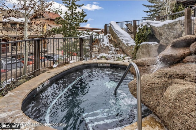 view of pool featuring an in ground hot tub and fence