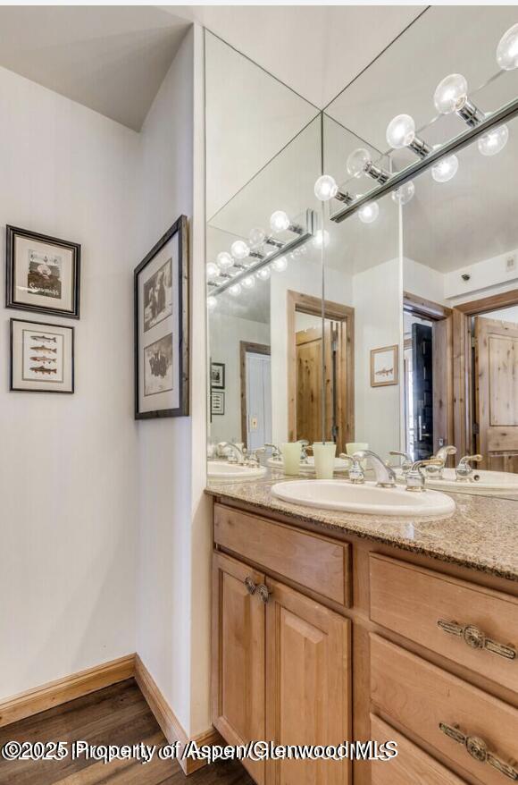 bathroom featuring wood finished floors, vanity, and baseboards