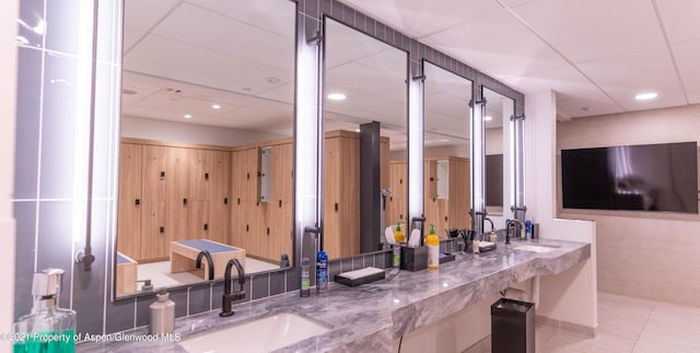 bar with stone countertops, sink, a drop ceiling, and tile patterned floors