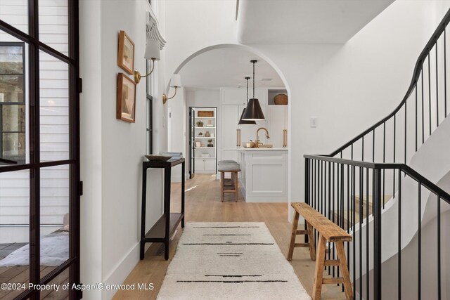 corridor with light hardwood / wood-style flooring and sink