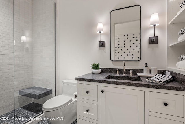 bathroom with a tile shower, vanity, and toilet