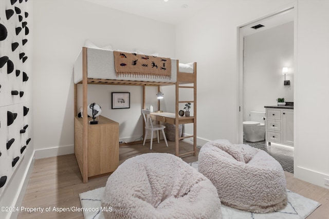 bedroom with light wood-type flooring and connected bathroom