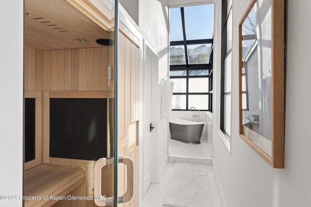 bathroom featuring a washtub, tile patterned flooring, and wood ceiling