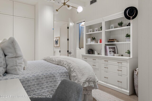 bedroom with light wood-type flooring, a closet, and wood walls