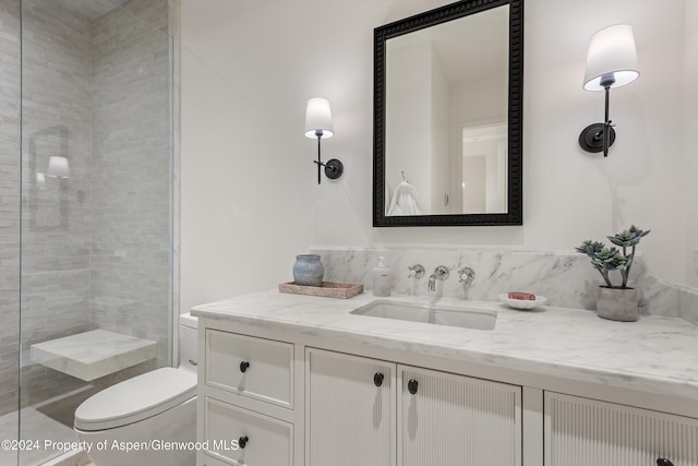 bathroom with vanity, toilet, and a tile shower