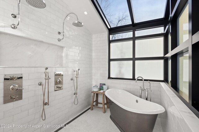 bathroom featuring tile patterned floors, a washtub, tile walls, and a skylight