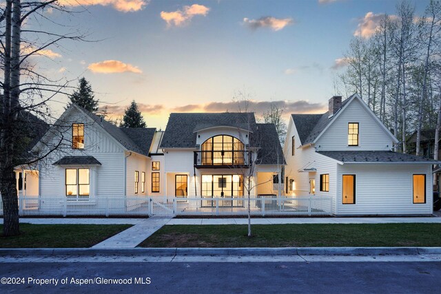 back house at dusk featuring a balcony