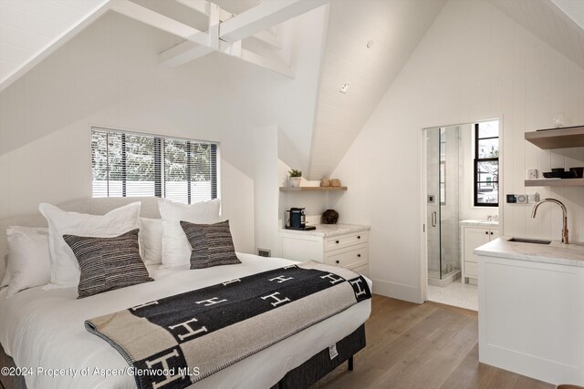 bedroom featuring light wood-type flooring, sink, high vaulted ceiling, and ensuite bath