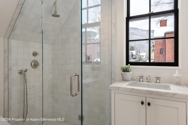 bathroom featuring plenty of natural light, vaulted ceiling, sink, and walk in shower