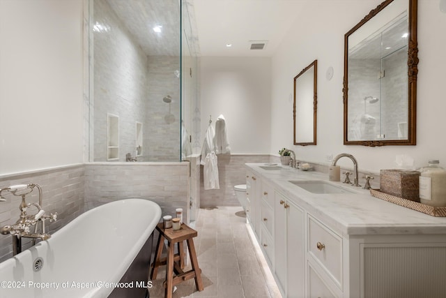 full bathroom with vanity, tile walls, tile patterned flooring, shower with separate bathtub, and toilet