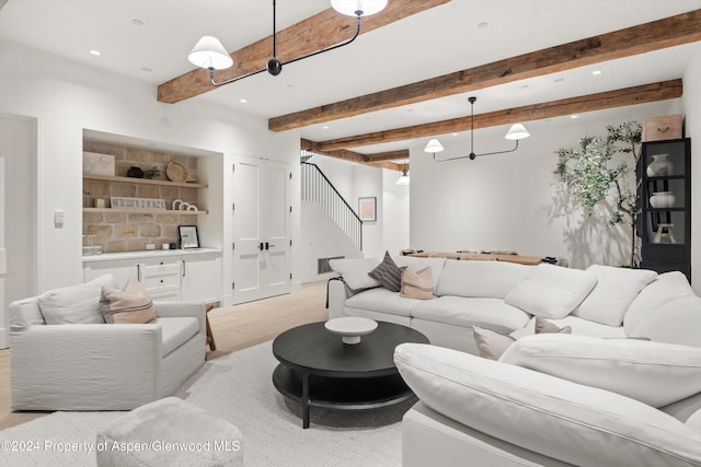 living room featuring beamed ceiling, light hardwood / wood-style flooring, and built in features