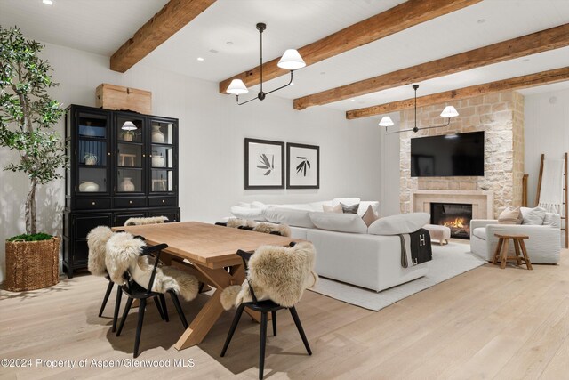 dining room featuring beam ceiling, light hardwood / wood-style floors, and a fireplace