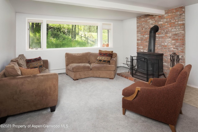 living room with beamed ceiling, a healthy amount of sunlight, a wood stove, and light carpet