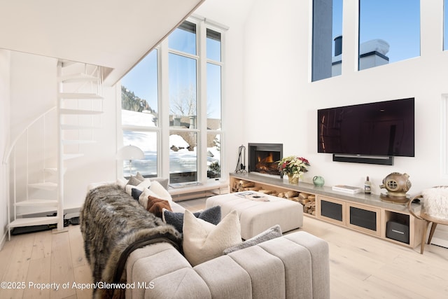 800 S Mill St Unit 304D, Aspen, CO 81611 - living room featuring a warm lit fireplace, a towering ceiling, and wood finished floors