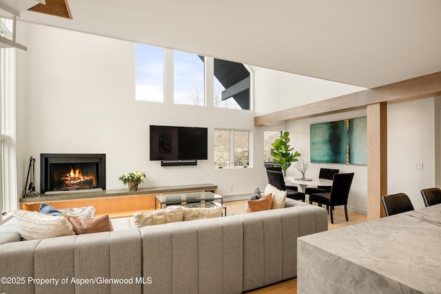 800 S Mill St Unit 304D, Aspen, CO 81611 - living area with a high ceiling, a warm lit fireplace, light wood-type flooring, and plenty of natural light